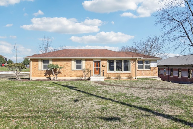 ranch-style house featuring roof with shingles, brick siding, and a front lawn