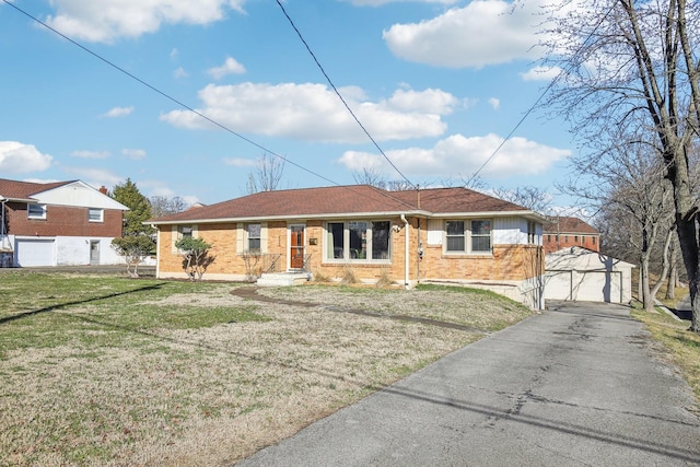 single story home with an outbuilding, brick siding, a front lawn, and a garage