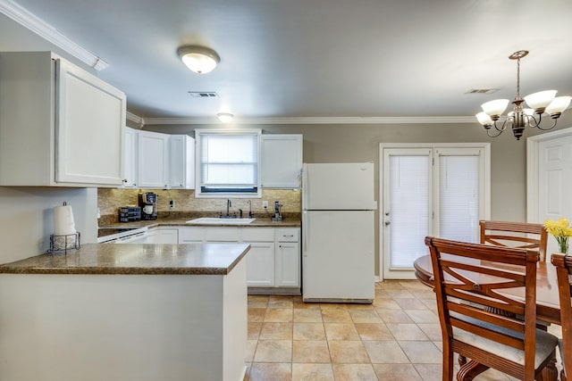 kitchen featuring tasteful backsplash, dark countertops, visible vents, freestanding refrigerator, and a sink