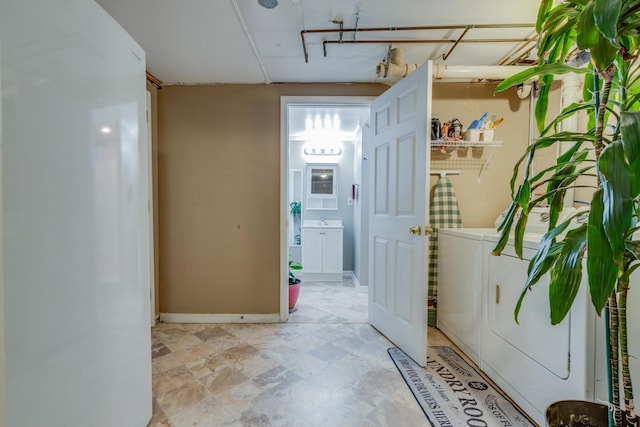 hallway with baseboards, a sink, and washing machine and clothes dryer