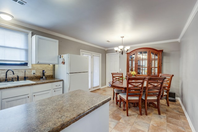 kitchen with a sink, baseboards, ornamental molding, freestanding refrigerator, and decorative backsplash