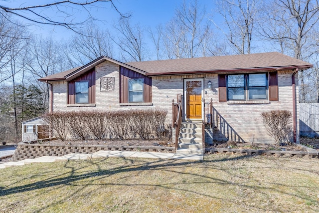 view of front of home with roof with shingles, a front lawn, and brick siding