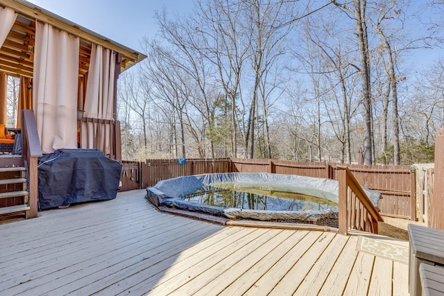 wooden deck with area for grilling and a fenced backyard