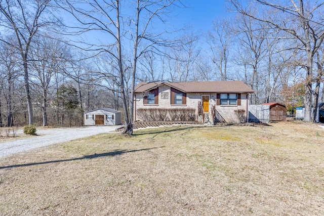 view of front of home featuring brick siding, a storage shed, a front lawn, and an outbuilding