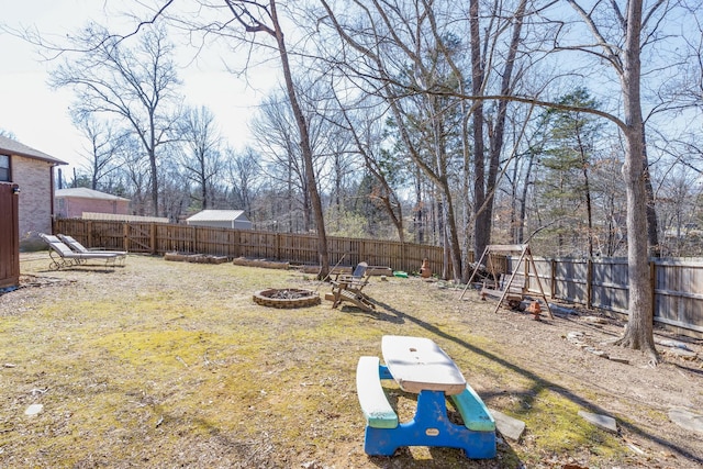 view of yard with a fire pit, a playground, and a fenced backyard