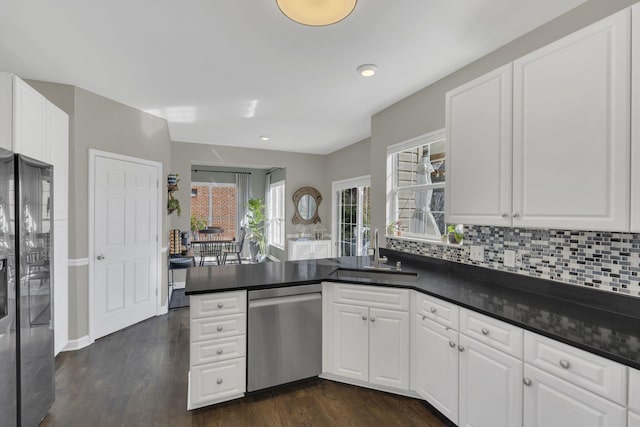 kitchen with dark countertops, dishwasher, refrigerator with ice dispenser, and a sink