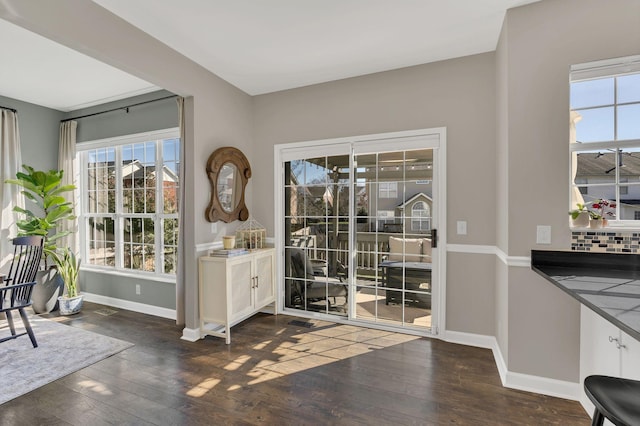 doorway with baseboards and hardwood / wood-style floors