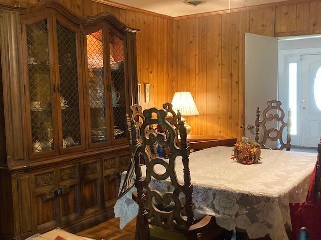 dining space featuring crown molding and wooden walls