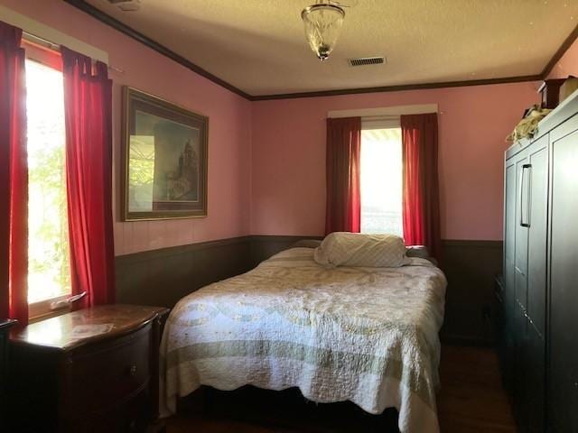 bedroom with visible vents, crown molding, and multiple windows