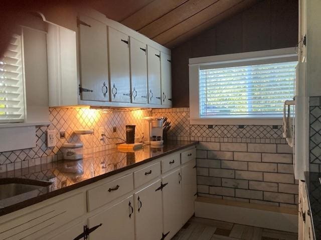 kitchen with lofted ceiling, white cabinetry, and dark countertops