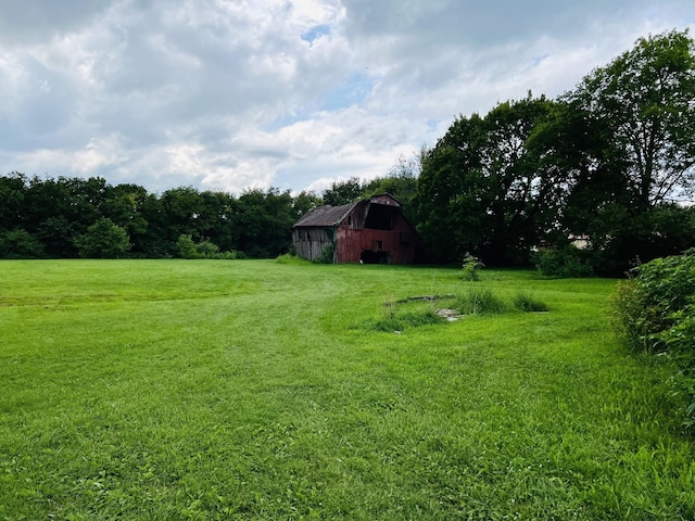 view of yard featuring a barn, a rural view, and an outbuilding