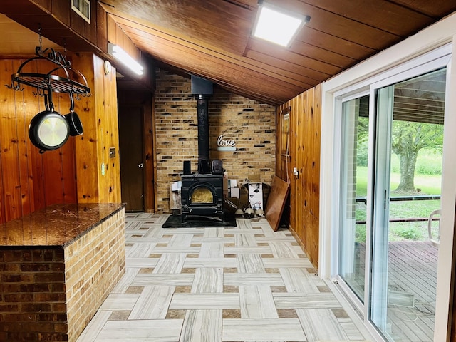 interior space with lofted ceiling, a wood stove, visible vents, and wood walls