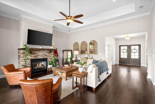 living area with a stone fireplace, wood finished floors, visible vents, french doors, and a tray ceiling