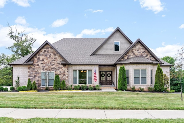 craftsman house with a front lawn, a shingled roof, and brick siding