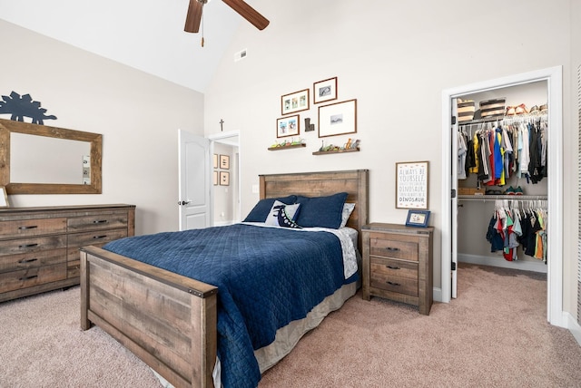 bedroom featuring a walk in closet, a closet, visible vents, light carpet, and high vaulted ceiling