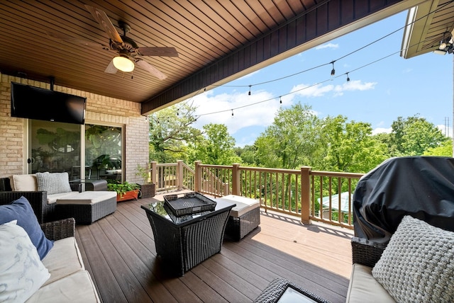 wooden deck with a ceiling fan, an outdoor living space with a fire pit, and area for grilling