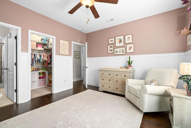 living area featuring ceiling fan, wainscoting, wood finished floors, and visible vents