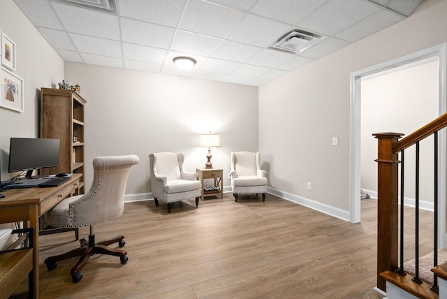 home office with light wood-style floors, a paneled ceiling, visible vents, and baseboards