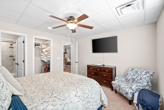 bedroom with a walk in closet, a paneled ceiling, light colored carpet, visible vents, and ceiling fan