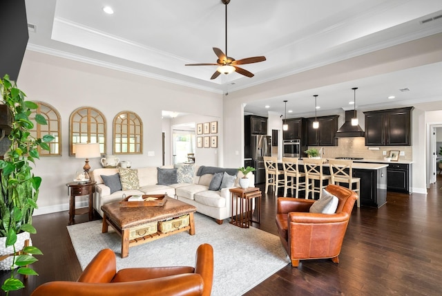 living area with visible vents, a tray ceiling, and dark wood-style flooring