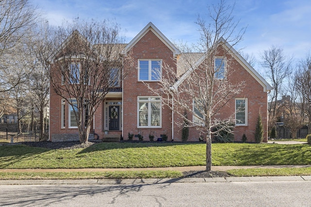 traditional-style home featuring a front yard, brick siding, and fence