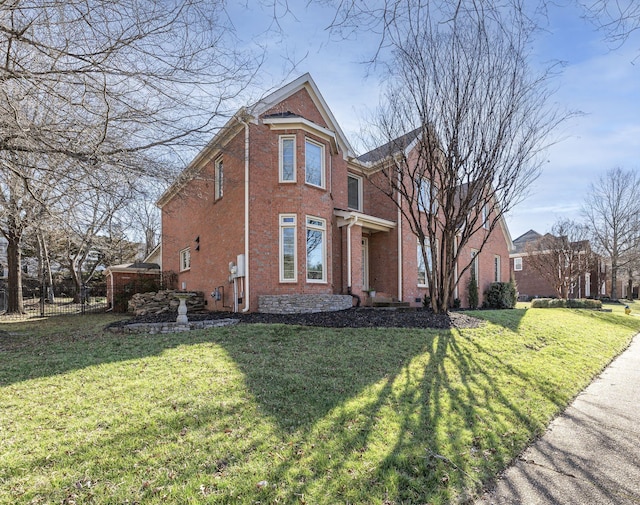 view of front facade with a front yard, fence, and brick siding