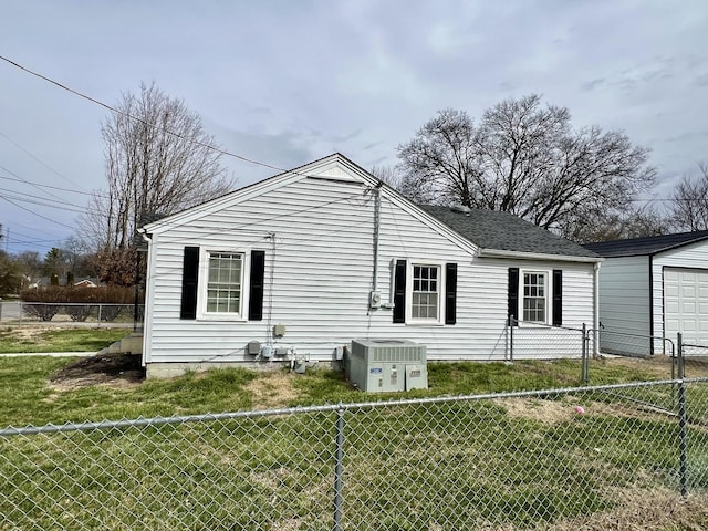 view of property exterior featuring an outbuilding, central AC, fence, a yard, and roof with shingles