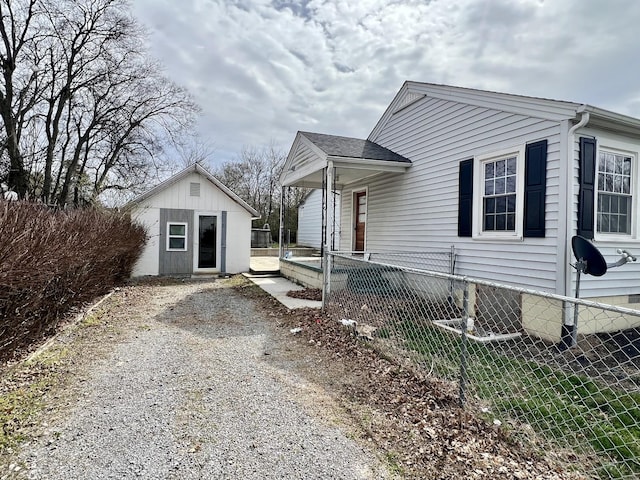 view of front of home with gravel driveway, fence, and an outdoor structure