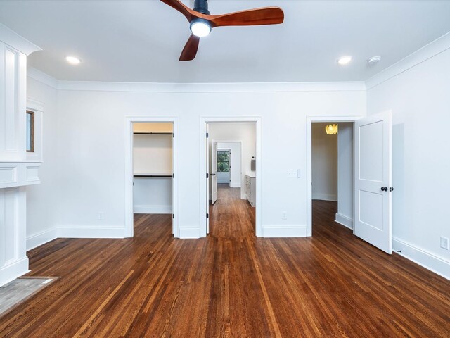 unfurnished bedroom with dark wood-style floors, a walk in closet, recessed lighting, ornamental molding, and baseboards