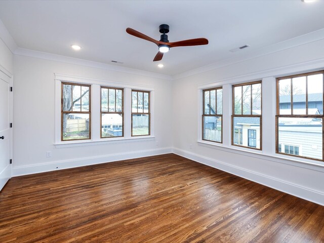 empty room featuring ornamental molding, dark wood finished floors, visible vents, and baseboards