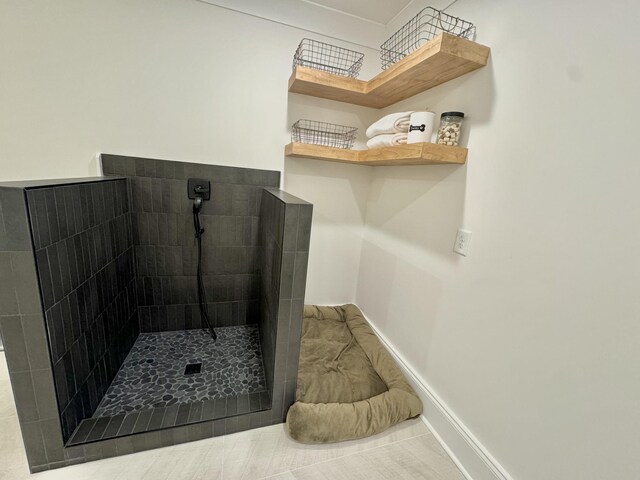 bathroom featuring a tile shower and baseboards