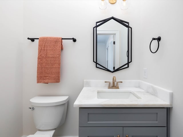 half bath featuring vanity and toilet