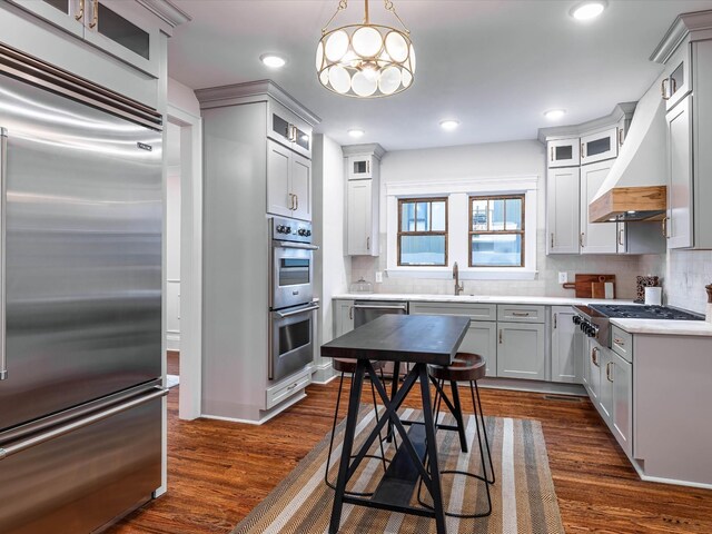 kitchen featuring stainless steel appliances, dark wood-type flooring, a sink, and backsplash