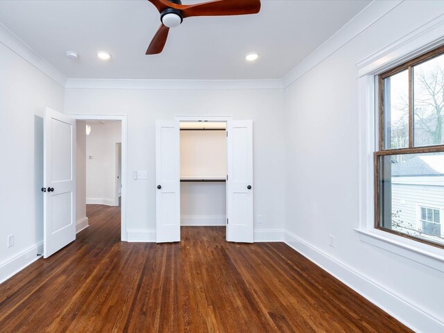 unfurnished bedroom featuring dark wood-type flooring, a ceiling fan, baseboards, ornamental molding, and a closet