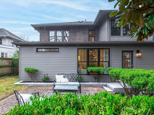 back of property with a patio area, fence, and brick siding