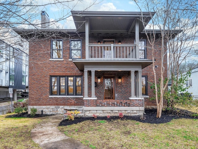 view of front of house featuring a balcony, covered porch, a chimney, and brick siding