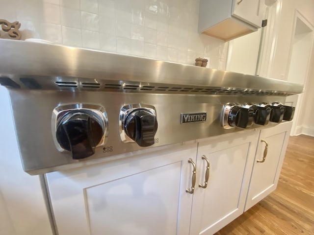 room details with tasteful backsplash, light countertops, white cabinets, and light wood-style floors