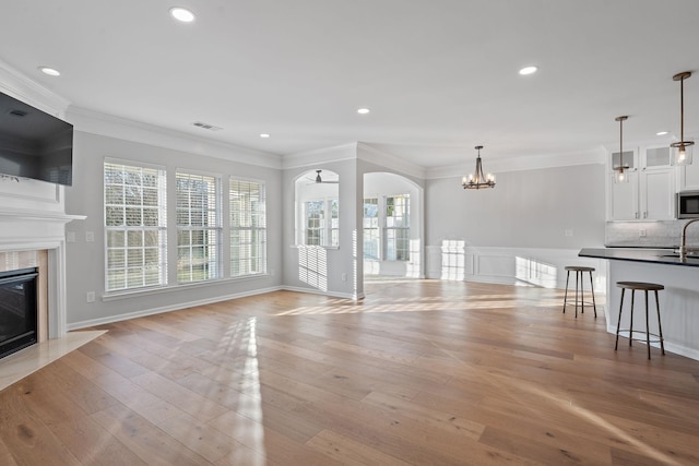 unfurnished living room featuring light wood-type flooring, a fireplace, visible vents, and a wealth of natural light