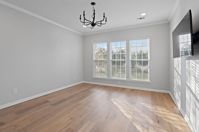 spare room with a chandelier, visible vents, baseboards, ornamental molding, and light wood finished floors