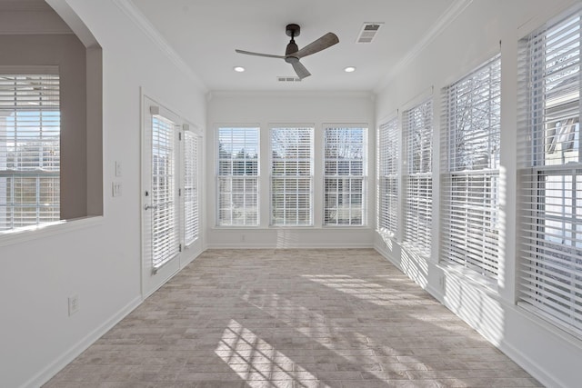 unfurnished sunroom featuring a ceiling fan, arched walkways, and visible vents