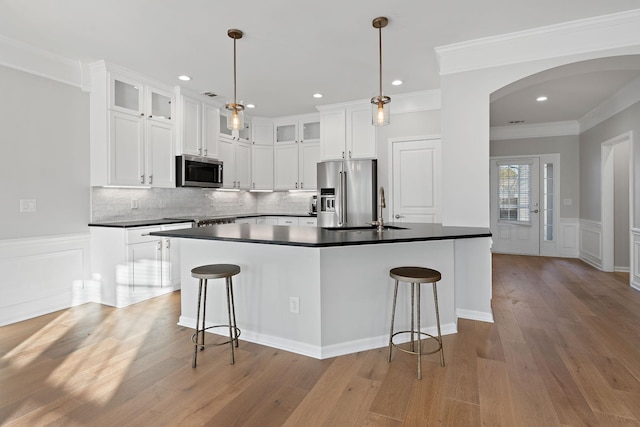 kitchen with arched walkways, appliances with stainless steel finishes, dark countertops, and a breakfast bar