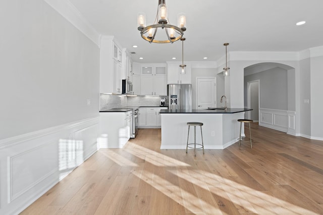 kitchen featuring arched walkways, dark countertops, appliances with stainless steel finishes, backsplash, and a sink