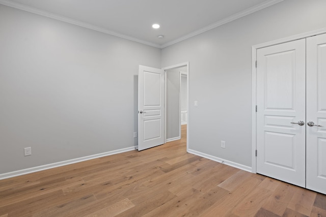 unfurnished bedroom featuring light wood-style floors, baseboards, and crown molding