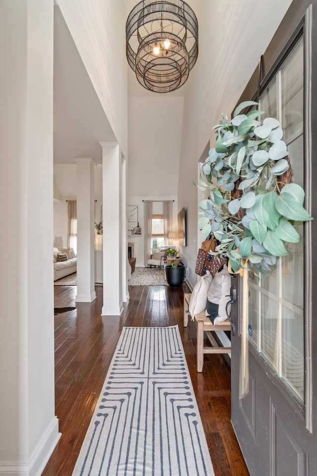 entryway with baseboards, a notable chandelier, a towering ceiling, and hardwood / wood-style floors