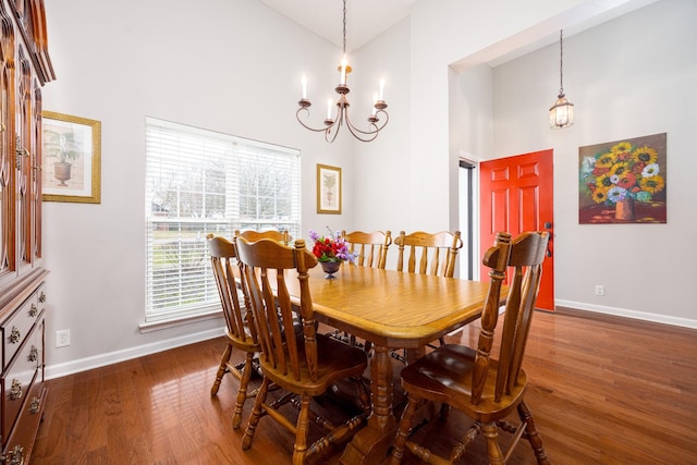 dining room featuring a high ceiling, baseboards, a chandelier, and wood finished floors