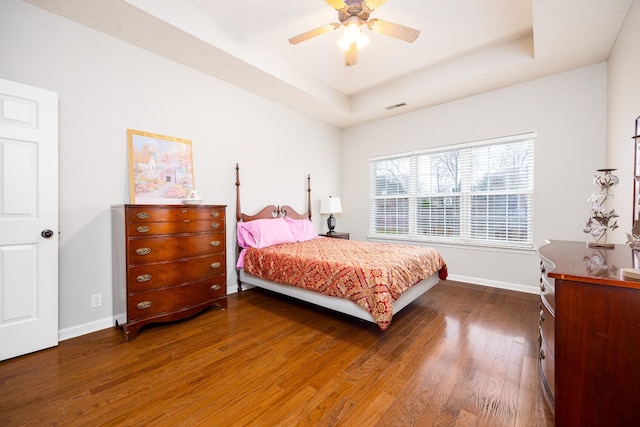 bedroom featuring visible vents, a raised ceiling, hardwood / wood-style flooring, and baseboards