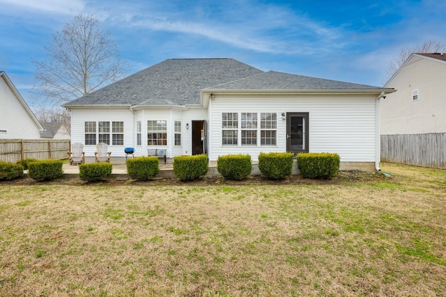 rear view of house featuring a patio, a lawn, fence, and roof with shingles