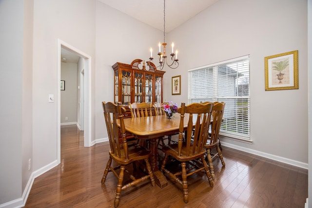 dining room with dark wood-style floors, high vaulted ceiling, a chandelier, and baseboards