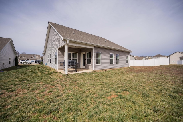 back of property featuring a shingled roof, a patio area, a lawn, and fence