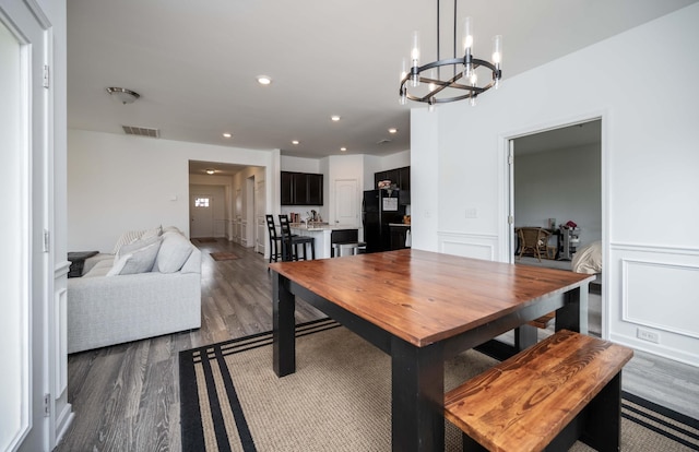 dining room featuring dark wood-style floors, visible vents, a decorative wall, and recessed lighting